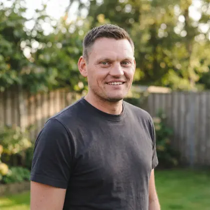 Remco, oprichter Westend Digital, staat lachend in een tuin met groene bomen op de achtergrond